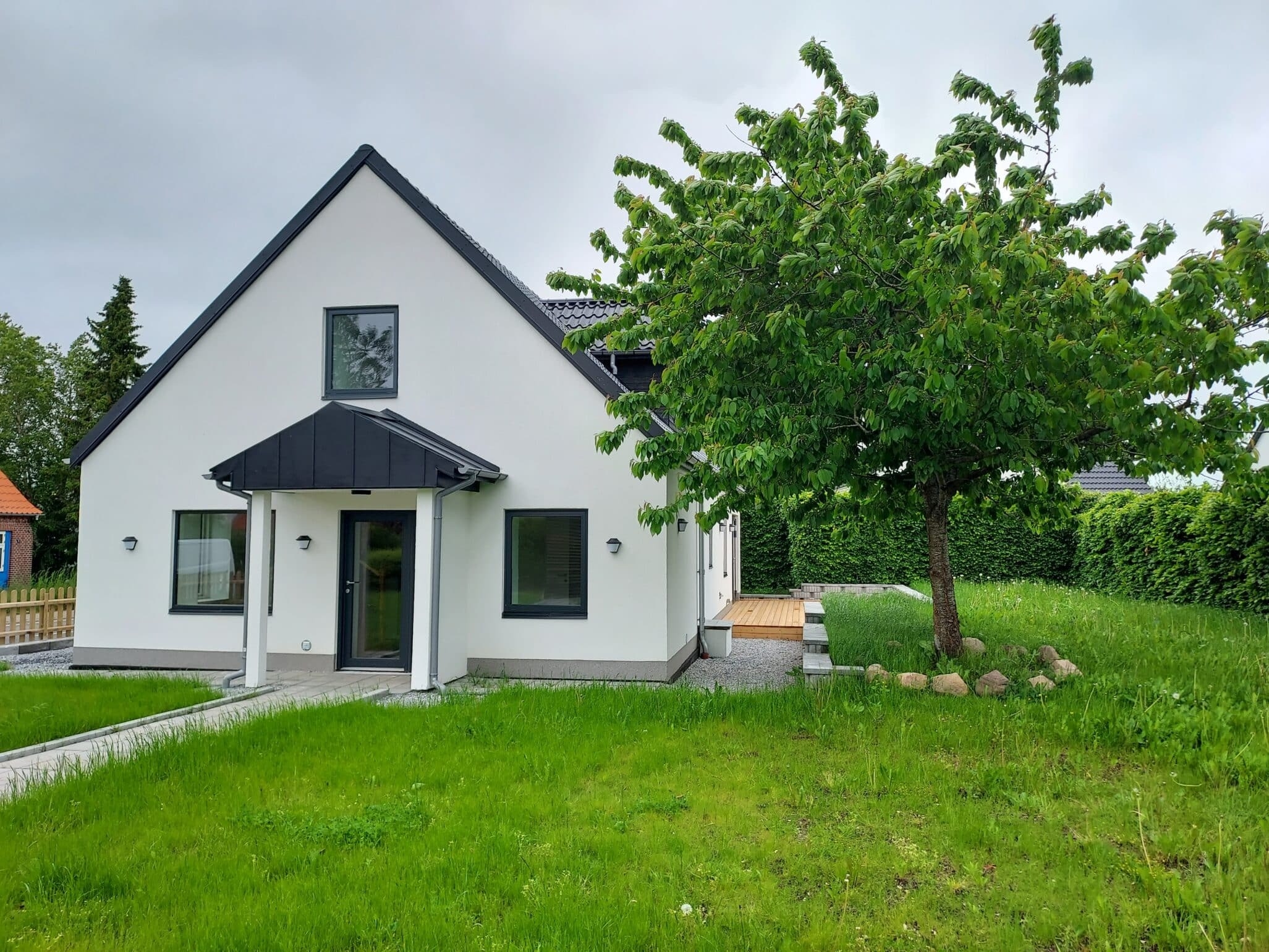 Ny- renoveret hvidt og sort hus med have.