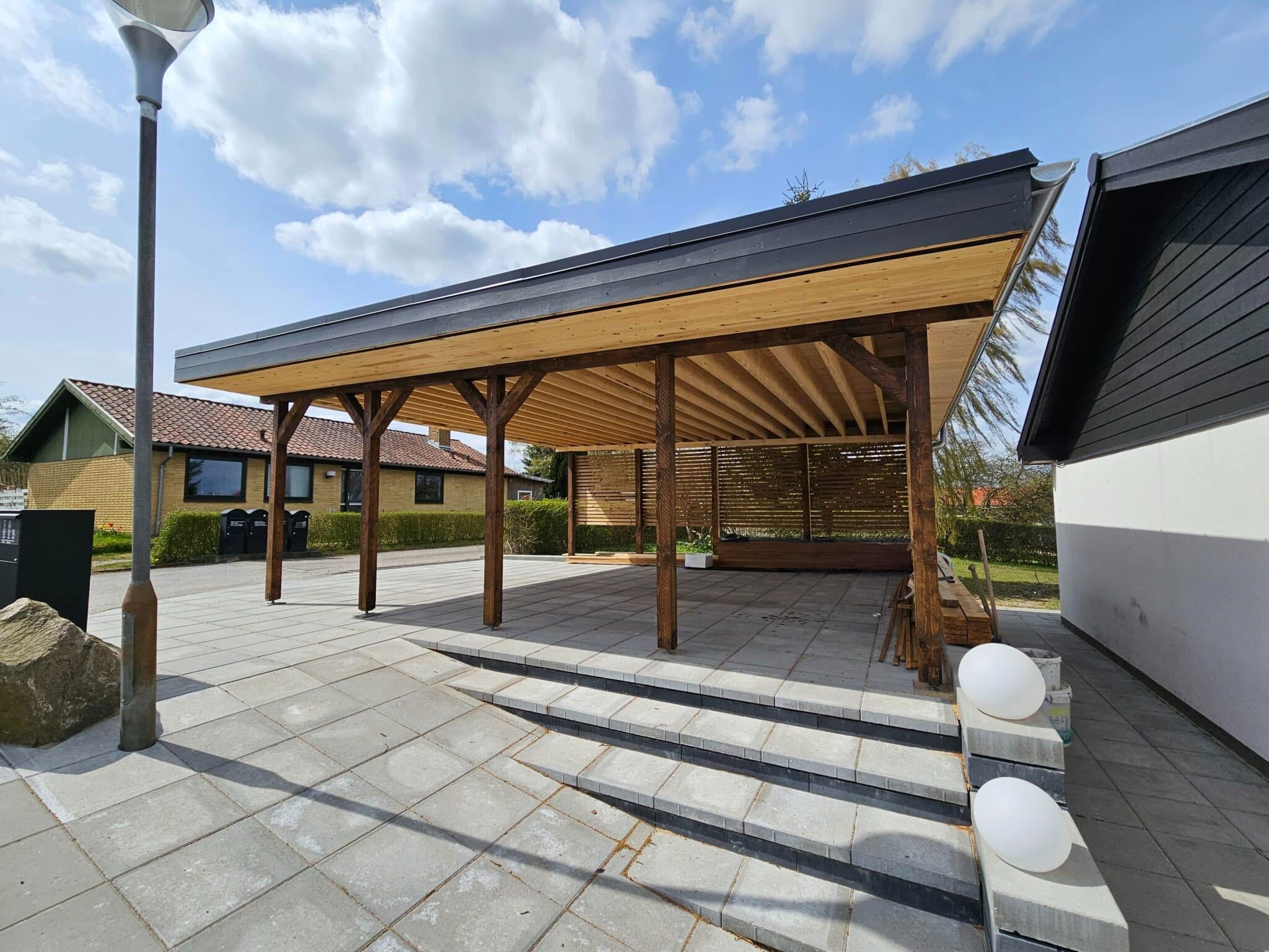 Tømrerprojekterne: akustiskpanel, carport og bygning med træpaneler.